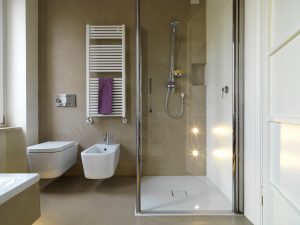 glass shower cubicle near to sanitary ware in a modern bathroom and radiator